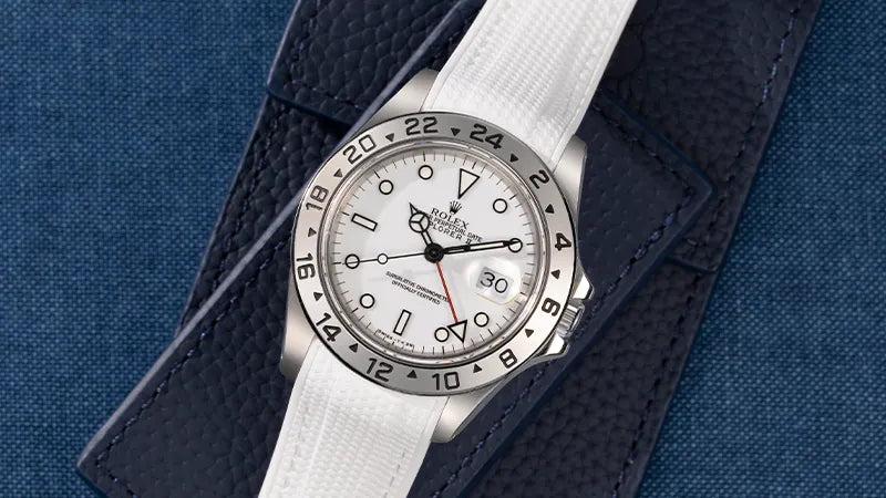 Rolex Explorer II 16570 with white dial and a premium white Rolex Explorer rubber strap, displayed on a navy leather background