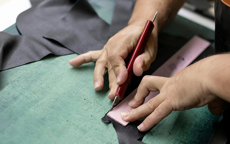 Hands cutting leather with a precision tool, showing the craftsmanship behind Wristbuddys watch straps.