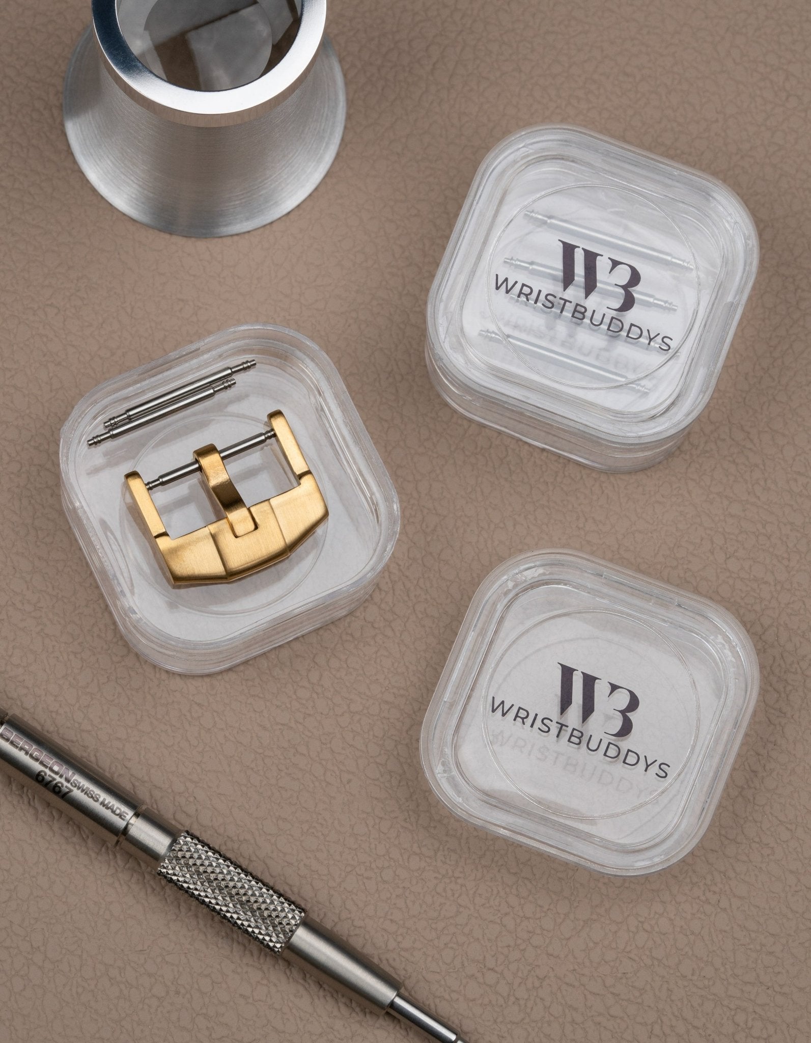 Premium buckle in gold for watch straps, shown with spring bars and Wristbuddys tool