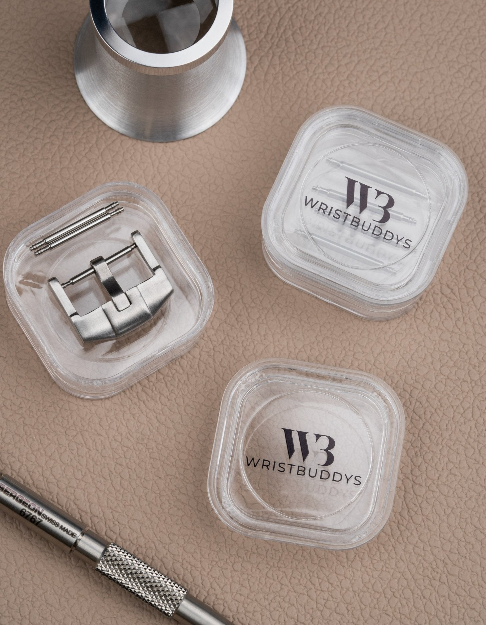 Premium buckle in silver for watch straps, shown with spring bars and Wristbuddys tool