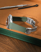 Military Green FKM rubber strap for Rolex Daytona 116520, integrated seamless fit with original clasp, resting on a leather valet tray.