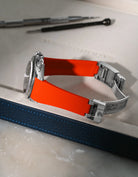 Red textured FKM rubber watch band for Rolex Daytona 116520, integrated design for original clasp, shown on a brown leather valet tray.