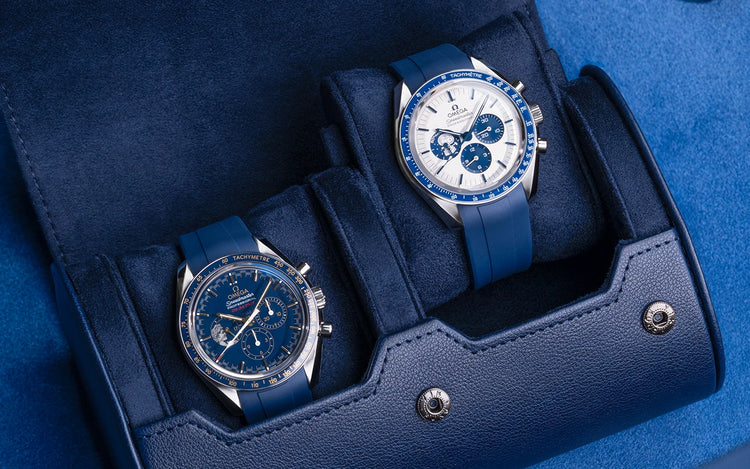 Close-up of navy blue 2 slot watch roll with suede interior holding two Omega watches one cushion lifted to display design details