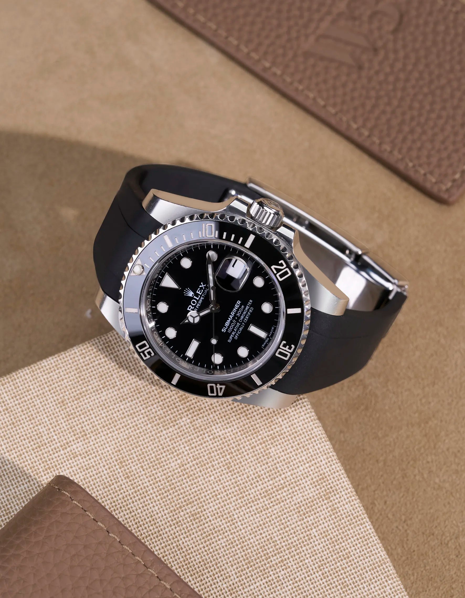 Black FKM rubber strap on Rolex Submariner 116610LN with clasp, flatlay on leather surface
