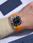 Wrist view of Rolex Submariner 16610/14060 on orange rubber strap with seamless original clasp integration