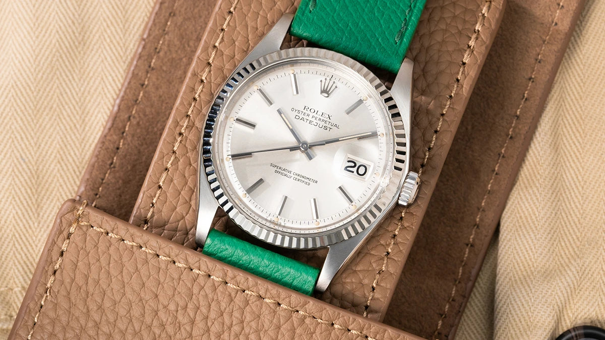 Luxury watch pouch holding a Rolex Datejust with a green leather strap, displayed on a beige background.