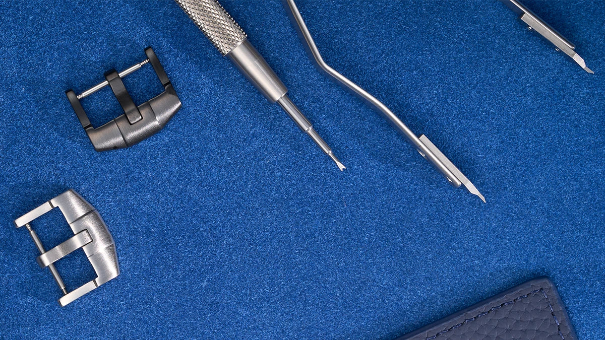 Watch tools on a blue surface, specifically designed for changing watch straps and spring bars.