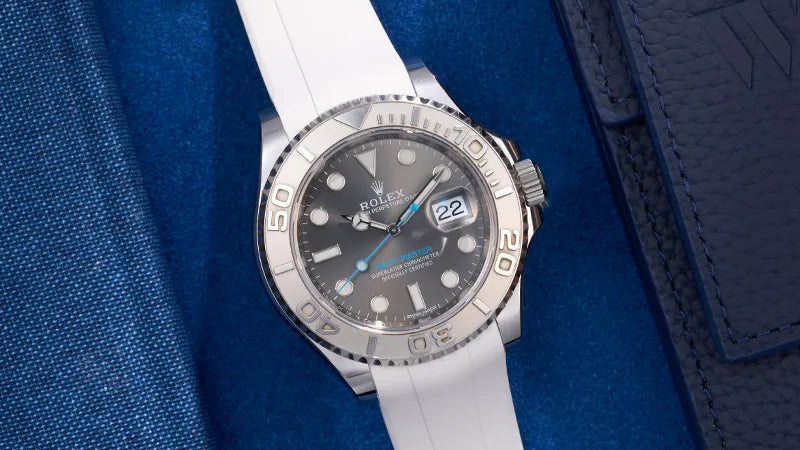 Rolex Yacht Master watch with a white rubber strap, combining luxury and durability, photographed on a blue background