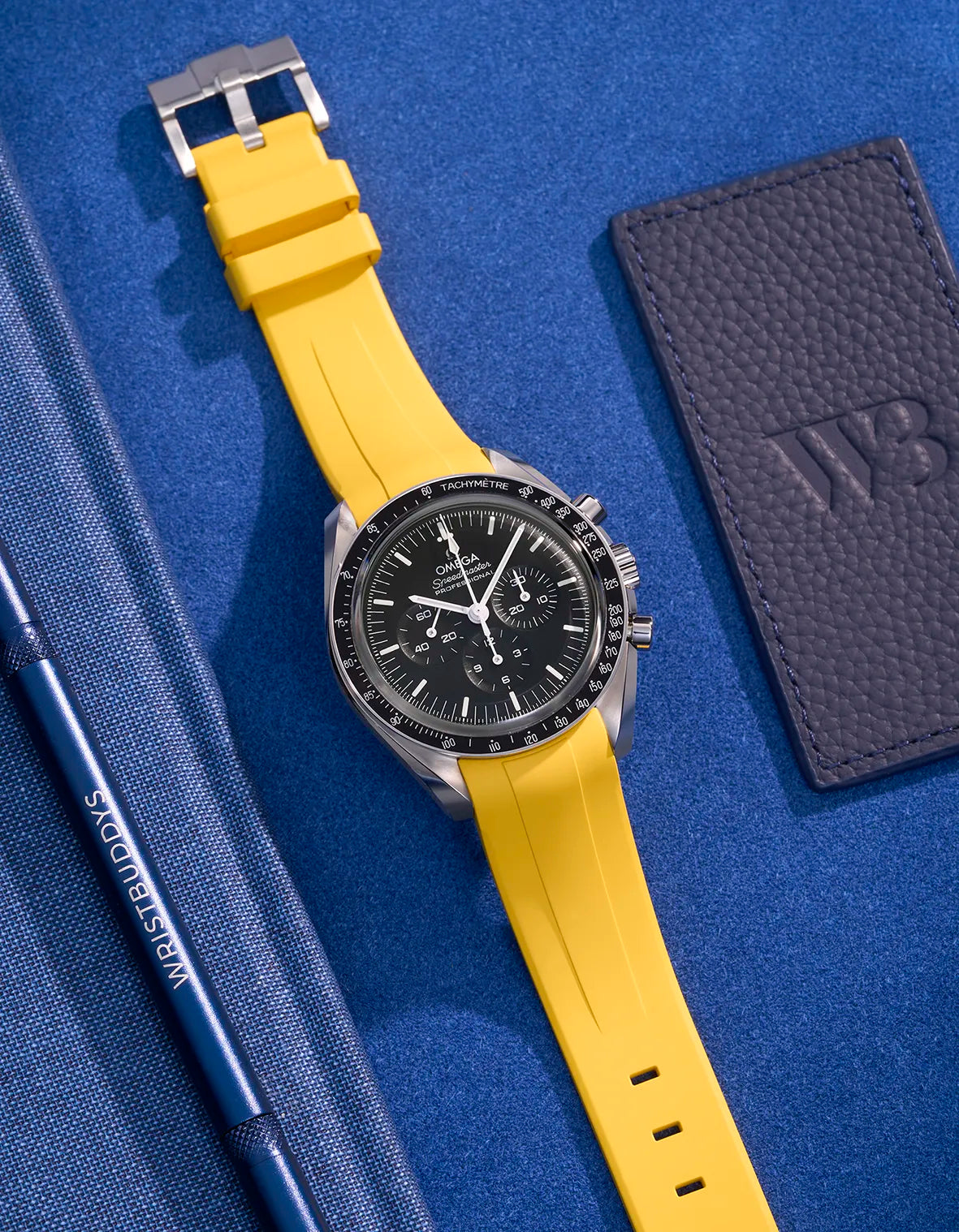 Yellow FKM rubber strap on Omega Speedmaster – flat lay with stainless steel clasp visible